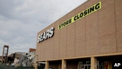 In this July 8, 2017, file photo people walk into a Sears store slated for closing that is next to a mall that is being torn down in Overland Park, Kan. Sears has filed for Chapter 11 bankruptcy protection Monday, Oct. 15, 2018.