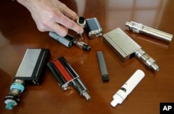 FILE - A high school principal Robert Keuther displays vaping devices that were confiscated from students in such places as restrooms or hallways at the school in Marshfield, Mass., April 10, 2018.