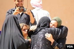 A family member takes pictures as a mother and daughter are reunited after nearly three years of separation in the days after Iraqi forces recaptured their family’s neighborhood in Mosul, Iraq, June 1, 2017. (H.Murdock/VOA)
