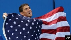 United States' Michael Phelps walks with his national flag during the medal ceremony for the men's 4 x 100-meter medley relay final during the swimming competitions at the 2016 Summer Olympics, Aug. 14, 2016, in Rio de Janeiro, Brazil.