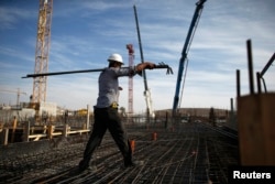 FILE - A laborer works on an apartment building project in a Jewish settlement known to Israelis as Har Homa and to Palestinians as Jabal Abu Ghneim in an area of the West Bank that Israel captured in the 1967 war and annexed to Jerusalem, Oct. 28, 2014.