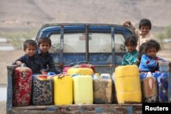 FILE - Children ride on the back of a truck loaded with water jerrycans at a camp for internally displaced people in the Dhanah area of the central province of Marib, Yemen, April 30, 2016.