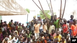 Kids from nearby villages gather at the Mbosse health clinic to watch a play on malaria prevention