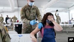 Leanne Montenegro, 21, covers her eyes as she doesn't like the sight of needles, while she receives the Pfizer COVID-19 vaccine at a FEMA vaccination center at Miami Dade College, Monday, April 5, 2021, in Miami.