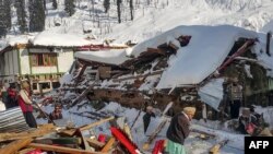 Penduduk setempat membuang puing-puing rumah yang runtuh akibat hujan salju lebat yang memicu longsoran salju di Lembah Neelum, di Kashmir, 14 Januari 2020 (Foto: AFP)