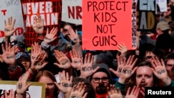 Para peserta unjuk rasa "March for Out Lives" mengacungkan poster bertuliskan slogan menuntut pengendalian penggunaan senjata yang lebih ketat, di Washington, 24 Maret 2018.
