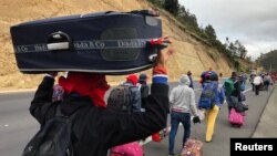 FILE - Venezuelan migrants walk along the Ecuadorean highway to Peru before new rules requiring they hold a valid passport kick in, at Tulcan, Ecuador, Aug. 21, 2018. 