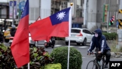 Seorang pengendara sepeda di samping dua bendera nasional Taiwan di Taipei. (Foto: AFP)