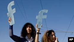 Protesters hold "f"s in recognition of social network site Facebook's role in the North African revolts, during a protest by thousands over civil rights, in Rabat, Morocco, March 2011.