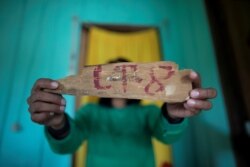 FILE - An indigenous woman of the Uru-eu-wau-wau tribe shows a piece of wood with a lot number removed from an area deforested by invaders in the village of Alto Jaru, at the tribe's reservation, near Campo Novo de Rondonia, Brazil, Feb. 1, 2019.