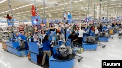 FILE - Cashiers work at the checkout lanes of a Walmart store in Los Angeles, Nov. 26, 2013. 