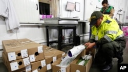 FILE - An anti-narcotics police officer inspect flowers at the El Dorado Airport, in Bogota, Colombia.