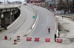 A Kashmiri man rides on a bicycle through a deserted road during a lockdown in Srinagar, Indian-controlled Kashmir, March 26, 2020.