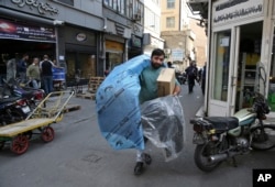 FILE - A man carries car parts at a market in downtown Tehran, Iran, Oct. 9, 2017. Iranians hope lifting of most international sanctions under Tehran’s 2015 nuclear deal with the West will revive their country's long-suffering economy.