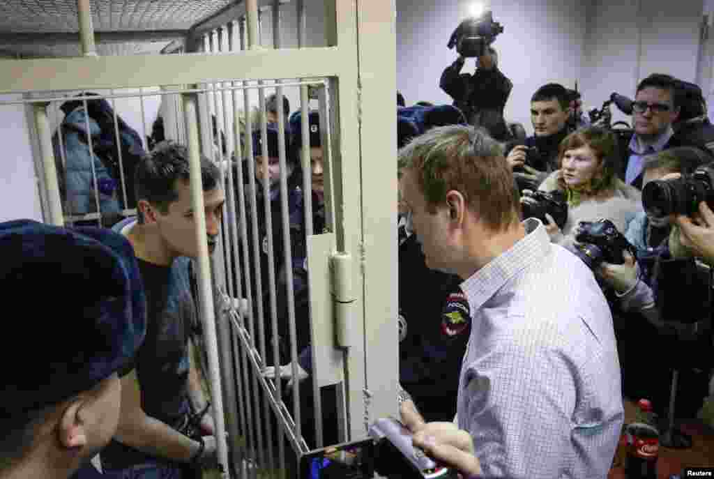 Russian opposition leader and anti-corruption blogger Alexei Navalny talks with his brother and co-defendant Oleg during a court hearing in Moscow, Dec. 30, 2014.