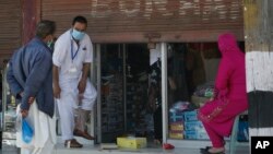 A Kashmiri man tries on a pair of shoes outside a shop, with it's shutters hald-closed, ahead of Eid al-Fitr during a nationwide lockdown to control the spread of coronavirus, in Srinagar, Indian controlled Kashmir, Saturday, May 16, 2020. India's…
