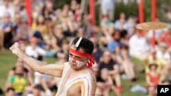 FILE - An Aboriginal man swings an instrument known as a bullroarer during the Wugulora Indigenous Morning Ceremony as part of Australia Day celebrations in Sydney, Australia, Jan. 26, 2020.