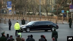 Security officials stand guard while a Mercedes limousine in a motorcade believed to be carrying North Korean leader Kim Jong Un passes along a street in Beijing, Wednesday, Jan. 9, 2019. 