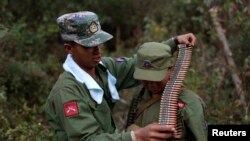FILE - A rebel soldier of Myanmar National Democratic Alliance Army (MNDAA) places a machine gun bullet belt around the neck of another soldier at a military base in Kokang region, March 10, 2015.