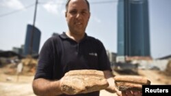 Diego Barkan, director of the excavation for the Israel Antiquities Authority, shows fragments of ancient basins unearthed at an archaeological dig in a future construction site in Tel Aviv, March 29, 2015. 