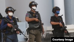 កម្លាំង​កង​រាជ​អាវុធហត្ថ​ឈរនៅមុខទ្វារចូលក្នុងគេហដ្ឋានរបស់ភូមិគ្រិះមួយ ដែល​ឧក្រិដ្ឋជន​៤​នាក់​បាន​បង្កើត​​ផែន​ការ​ចូល​ជំរិត​​និង​ប្លន់​សម្លាប់​ ​ក្នុង​បុរី​អង្គរ​ភ្នំពេញ ​ខណ្ឌ​សែន​សុខ រាជធានី​ភ្នំពេញ កាលពីថ្ងៃទី១ ខែមីនា ឆ្នាំ២០២១។ (រូបថតដោយបញ្ជាការដ្ឋានកងរាជអាវុធហត្ថរាជធានីភ្នំពេញ)