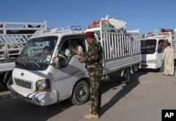 FILE - Iraqi security forces check identification documents at a checkpoint near the entrance to Ramadi, 70 miles (115 kilometers) west of Baghdad, Iraq, April 3, 2016.