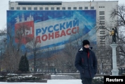 在亲俄反政府武装控制的顿涅茨克市，一名行人走过展示“我们是俄罗斯的顿巴斯”标语的宣传横幅。(2022年1月24日)