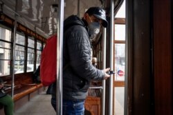 A man wearing a protective mask steps off an empty tram in downtown Milan, Italy, Feb. 26, 2020.