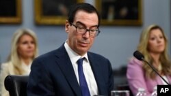 美国财政部长姆努钦(Steven Mnuchin)在华盛顿国会山作证时阅读手机上的一条信息（2020年3月11日）。