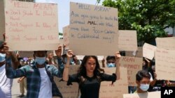 Anti-coup protesters hold slogans calling the attention of an ASEAN regional meeting during a rally on April 20, 2021, in Yangon, Myanmar, as the European Union expanded its sanctions against Myanmar's military leaders and army-controlled companies.