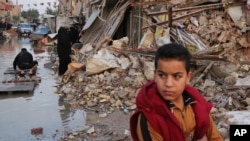 Civilians inspect the aftermath of a car bomb explosion in the Shiite enclave of Sadr city, Baghdad, Iraq, Dec. 5, 2014.