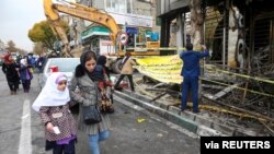 FILE - People walk near a burned bank after protests against increased fuel prices, in Tehran, Iran, Nov. 20, 2019. 