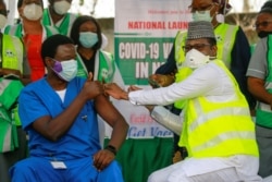 Dr Ngong Cyprian receives his first dose of the Oxford/AstraZeneca coronavirus disease (COVID-19) vaccine from Dr Faisal Shuaib, Executive Director and Chief Executive Officer of the National Primary Health Care Development Agency, in Abuja.