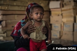 A Rohingya refugee mother holds her recovering baby who has received treatment for malnutrition at an Action Against Hunger clinic in Ukhiya, Bangladesh, April 18, 2018. One-fifth of the children in the camps are malnourished, with 12 percent suffering from severe stunting as a result of hunger.