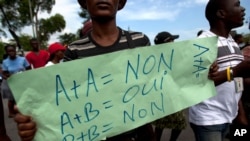 FILE - A protester holds a sign that reads in French "A+A=No. A+B=Yes. B+B=No" during an anti-gay demonstration in Port-au-Prince, Haiti.