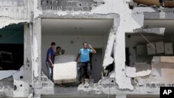 Mideast Israel PalestiniansPalestinians salvage what they can of their belongings from the rubble of their destroyed apartment in a building hit by an Israeli strike in Beit Lahiya, northern Gaza Strip, Aug. 4, 2014. 
