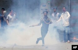 FILE - A Kashmiri Muslim protester throws back a teargas shell at Indian paramilitary soldiers in Srinagar, Indian-controlled Kashmir, July 10, 2016.