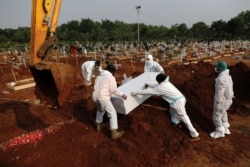 Pekerja mengenakan Alat Pelindung Diri (APD) mengubur peti mati pria berusia 72 tahun yang meninggal karena COVID-19 di area pemakaman di Bekasi, 15 Juli, 2021. (Foto: REUTERS/Willy Kurniawan)