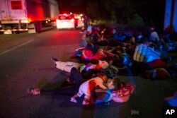 Early in the morning migrants sleep next to the highway waiting for a ride, as a thousands-strong caravan of Central American migrants slowly makes its way toward the U.S. border, between Pijijiapan and Arriaga, Mexico, Oct. 26, 2018.