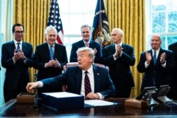 Treasury Secretary Steven Mnuchin, left, Vice President Mike Pence, second from right, and Republican lawmakers applaud President Donald Trump during a signing ceremony of a $2.2 trillion stimulus measure, at the White House, in Washington, March 27, 2020.