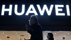 FILE - Residents pass by a Huawei electronics store in Beijing, April 12, 2021.