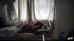 FILE - Mbuh Ronaldo lies in a hospital bed in Buea, the capital of Cameroon's majority English-speaking southwest region, Oct. 4, 2018. Medical doctors are overwhelmed with patients as many of their colleagues seek better pay and working conditions elsewhere. 