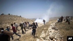 Palestinians run from tear gas fired by Israeli soldiers during a demonstration against the expansion of nearby settlements at the West Bank village of Dier Qadis, near Ramallah, June 15, 2011.
