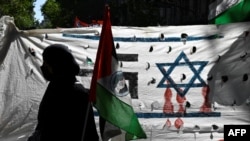 Seorang pengunjuk rasa memegang bendera Palestina saat unjuk rasa mendukung rakyat Palestina di depan kedutaan Israel di Buenos Aires, pada 9 Oktober 2023, setelah Israel memberlakukan pengepungan total di Jalur Gaza dan memutus pasokan air. (Foto: AFP)