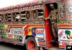 A Pakistani soldier stands guard in a bus carrying election staff and polling related material to stations in Karachi, Pakistan, July 24, 2018.