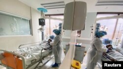 A medical staff is reflected in a mirror as she attends to a COVID-19 patient at a special ward at Arwyp Medical Centre, as South Africa is about the reach a milestone of 1 million infections, in Kempton Park, Dec. 25, 2020.