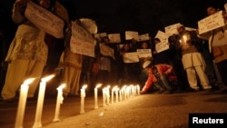 A boy places a candle as demonstrators hold placards during a candlelight march for a gang rape victim, who was assaulted in New Delhi, January 16, 2013. 