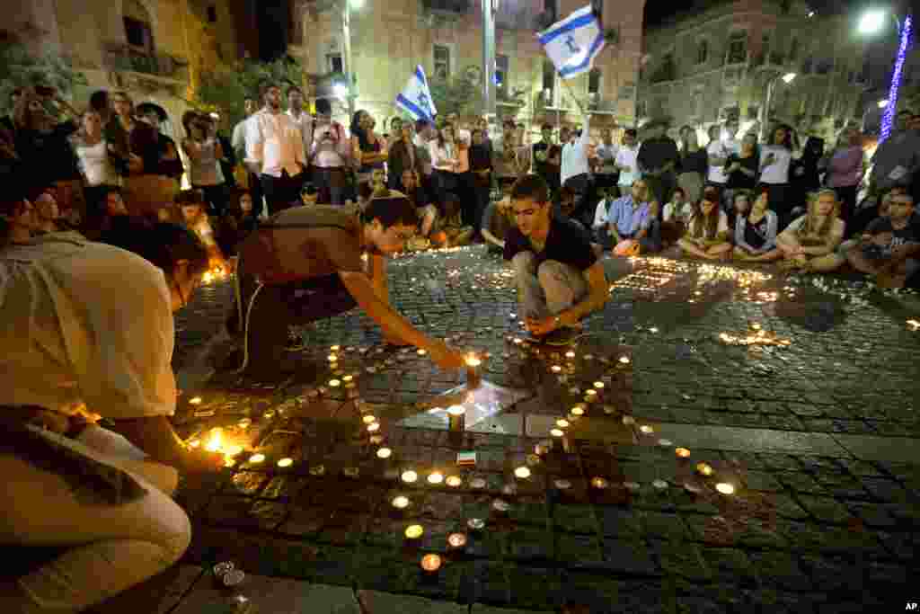 Israelis light candles as they gather in Jerusalem after the announcement that the bodies of the three missing teenagers were found near the West Bank town of Hebron, June 30, 2014. 