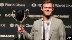 The reigning chess world champion, Norway's Magnus Carlsen, celebrates with the trophy after retaining the title in London, Nov. 28, 2018. Carlsen defeated American challenger Fabiano Caruana 3-0 in rapid tiebreaker games.
