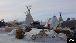  Both chopped firewood and donated wood for building shelter were buried under snow this week as a blizzard passed through the camp (E. Sarai / VOA)